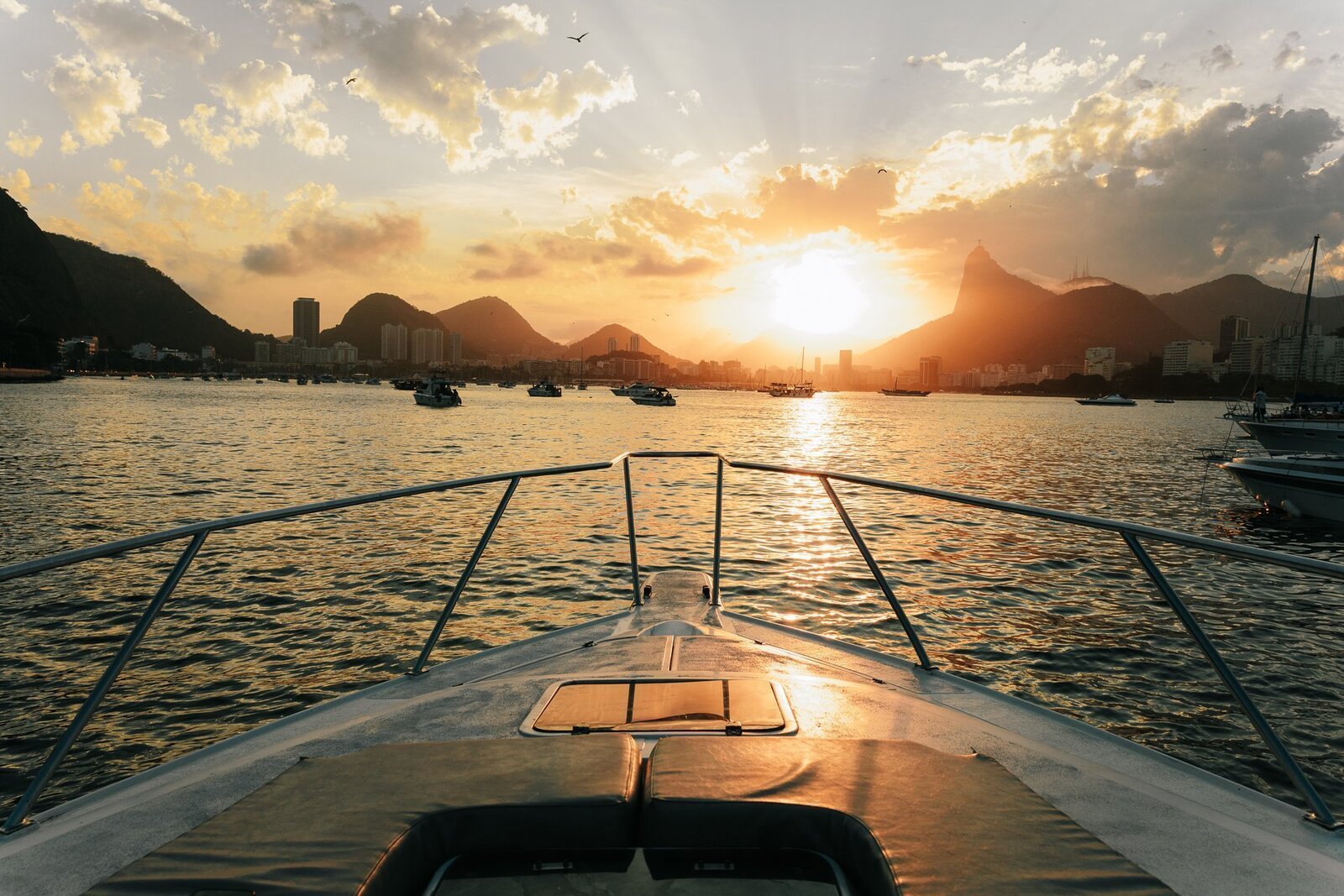 Lancha navegando na Baía de Guanabara com vista para o Cristo Redentor ao pôr do sol