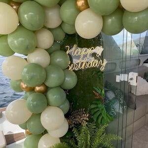 Decoração de aniversário na lancha com balões verdes e letreiro Happy Birthday neon